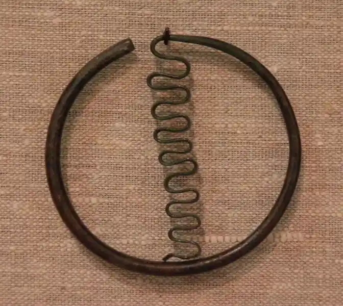 A wavy snake-like symbol inside a thick circle made of metal